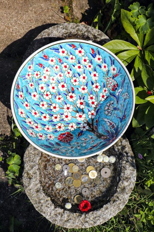 The inside of a ceramic bowl illustrated with the tree of life in blue, red,turqouise colors