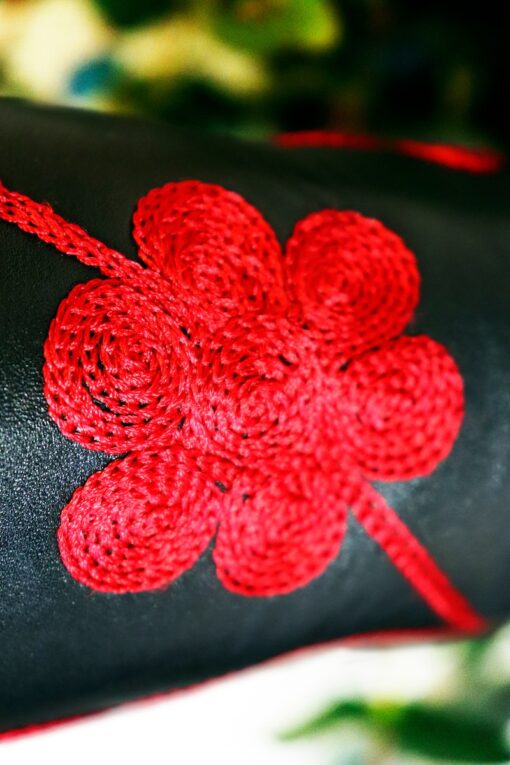 Close up of flower embroidered on a black long leather boot in handmade quality