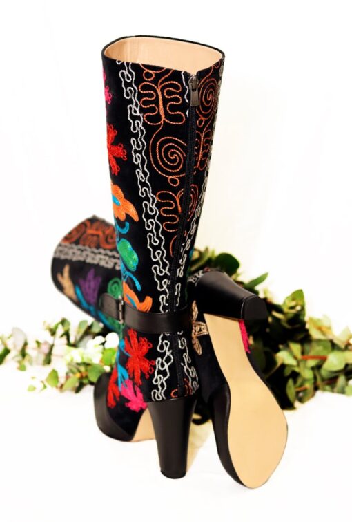 The back side of a pair of long-shafted boots with colorful embroidery and in leather and textile