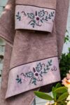 Handmade embroidery in dusty green, rose and darkrose colors decorating the border on an organic towel set